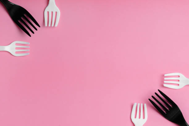 istock White and black plastic forks and transparent plastic bag on a pink background. 1243260136