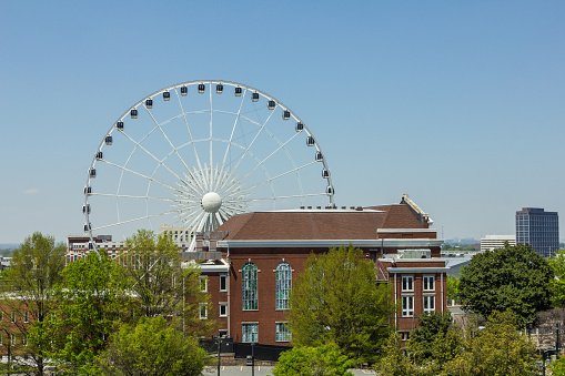 Giant white ferris wheel behind a vintage red brick building in urban Atlanta Georgia on clear blue day