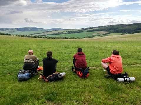 Group of backpackers - tourist sitting on the meadow and have beautiful view on Carpathian Mountains