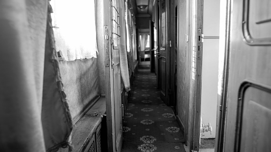 Black and white photo of long narrow corridor in vintage train car