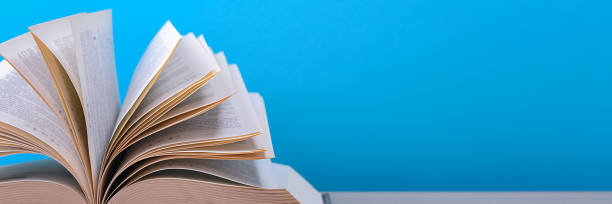 istock The book is open, lying on the table, sheets fanned out on a blue background. 1243340374