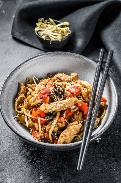 udon stir-fry noodles with chicken meat and sesame.  black background. top view - teriyaki broccoli carrot chicken imagens e fotografias de stock