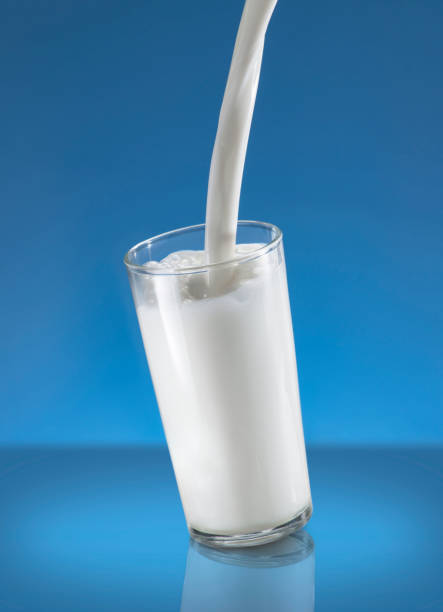 istock Pouring Milk Splash in A Glass Over Blue Background 1243343255