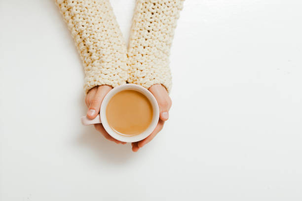 istock Female hands holding cups of coffee on white table background 1243354076