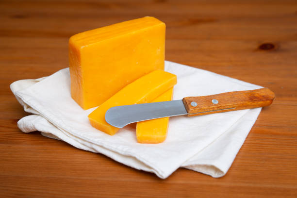 istock Yellow cheese and knife laying on white cloth 1243354694