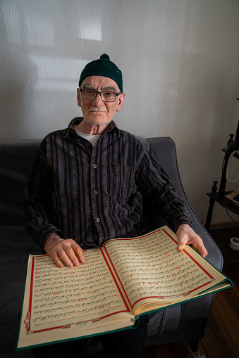 Muslim man reading Quran and praying at home in Ramadan, Turkey