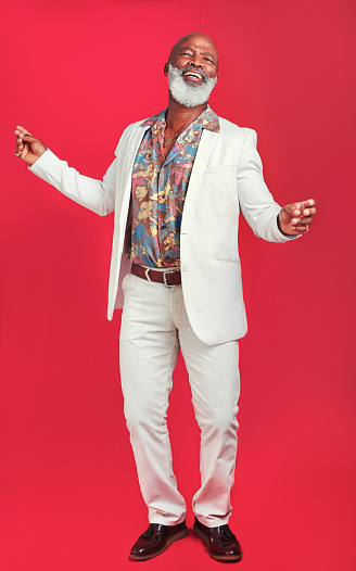 Studio shot of a man wearing vintage clothes while dancing against a red background