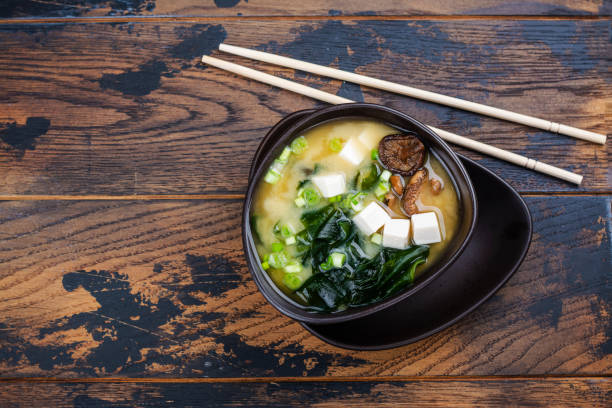Traditional miso soup Japanese traditonal miso soup with wakame seaweeds, tofu and shiitake mushrooms on bamboo mat. Copy space miso sauce stock pictures, royalty-free photos & images