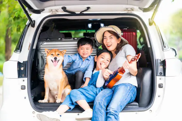 Photo of Pet lover. Happy asian children and Mother with shiba inu sitting and Sing Song in car.