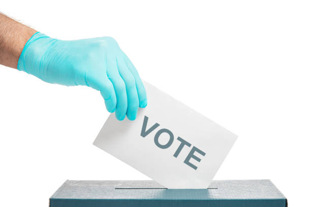 Elections. Male hand in protective glove putting a ballot with inscription vote into a box isolated on a white background.