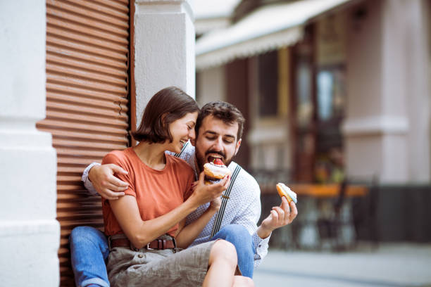 istock Couple eating doughnuts on street. 1243379942