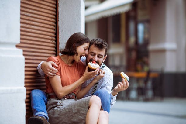 istock Couple eating doughnuts on street. 1243379958
