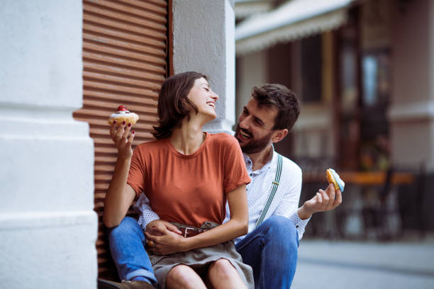 istock Couple eating doughnuts on street. 1243379960