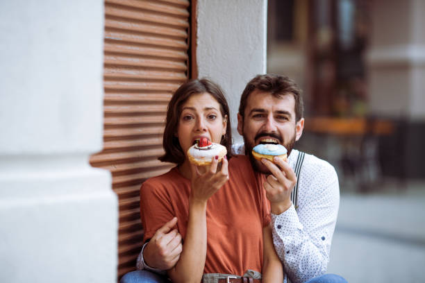 istock Couple eating doughnuts on street. 1243381050