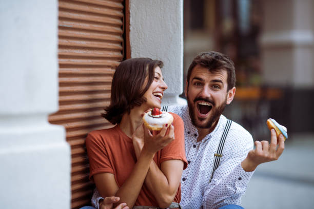 istock Couple eating doughnuts on street. 1243381584