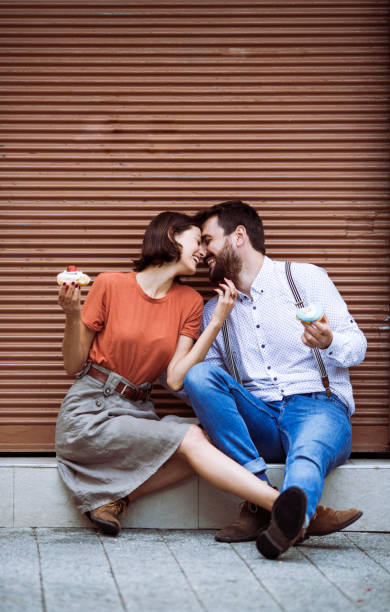 istock Couple eating doughnuts on street. 1243382125