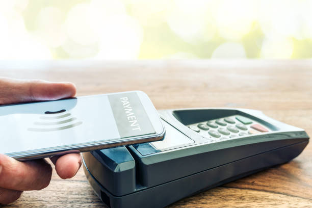istock person holding phone against POS payment terminal 1243387456