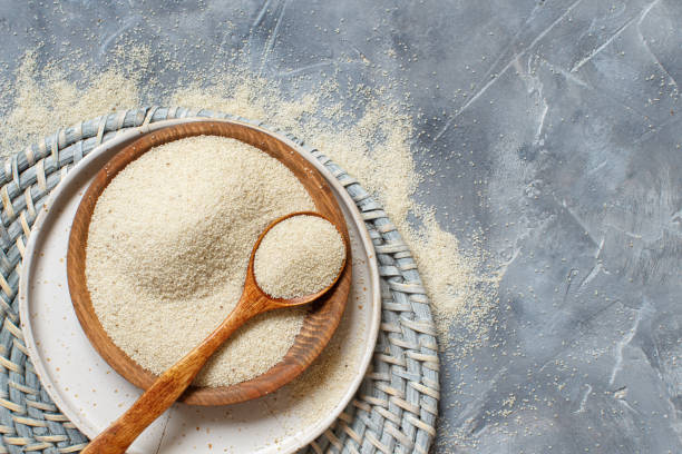 istock Raw uncooked fonio seeds with a spoon on a plate on grey background 1243397409