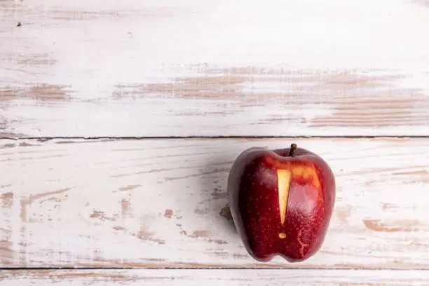 Red shiny delicious apple with an exclamation mark sign carved into it, photographed directly from above while placed on white painted aged pine timber floor boards. Ideal for many concept with plenty of copy space for your message and ideas, but mainly aiming to represent healthy eating, an "alertness" for nutrition - importance of nutrition, ripe fruit, healthy lifestyle, warning sigh, healthcare and medicine, carving - craft producetc. Shot on Canon EOS R system in studio for highest quality and resolution.