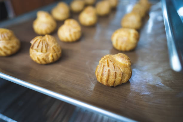 istock Close up choux baked home made  fresh crispy eclairs and profiteroles. Making desserts and sweets on an industrial scale, industry, background.Choux is a traditional french dessert. 1243412540