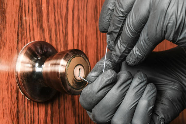 thief in black gloves opens a wooden door with a simple lock using ordinary steel wire. concept of enhanced home protection - 2603 imagens e fotografias de stock