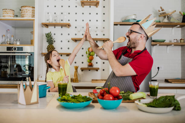 Father and his little cute daughter having fun in kitchen Young father and his daughter are in the kitchen, they are singing and laughing dancing dad stock pictures, royalty-free photos & images