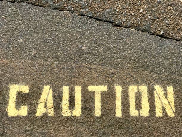 istock Caution Stencil Letter Warning Sign on Asphalt Pavement 1243433411