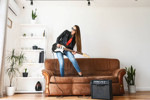 donna con una chitarra elettrica balla su un divano - guitar electric guitar modern rock metal foto e immagini stock