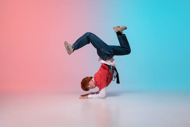 istock Boy dancing hip-hop in stylish clothes on gradient background at dance hall in neon light. 1243448808