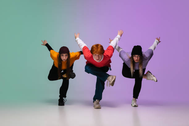 Group of teens, boys and girls dancing hip-hop in stylish clothes on gradient studio background in neon light. Group of teens, boys and girls dancing hip-hop in stylish clothes on colorful gradient studio background in neon light. Youth culture, movement, style and fashion, action. Fashionable portrait. rap kid stock pictures, royalty-free photos & images