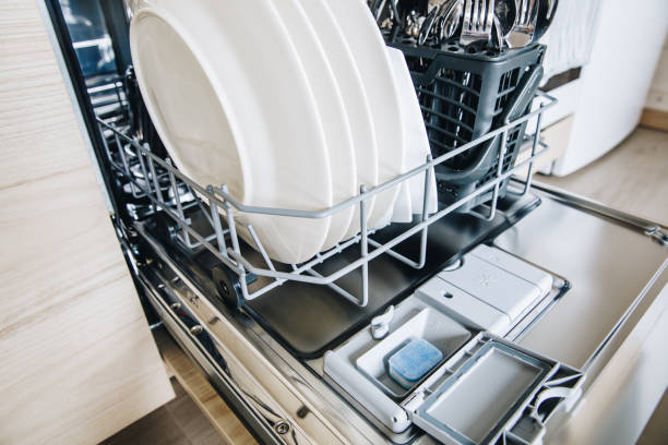 istock Blue colorful dishwasher detergent tablet for dishwashing machine. Open dishwasher with clean glasses and dishes close-up. 1243449669