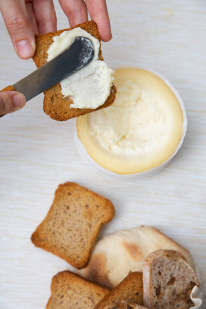 istock Unrecognizable person spreading soft cheese on toasted bread 1243454915