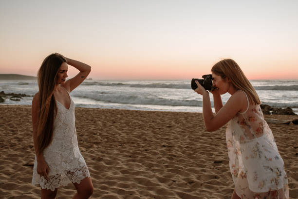 istock Two young women using a DSLR camera and posing at the beach 1243458864