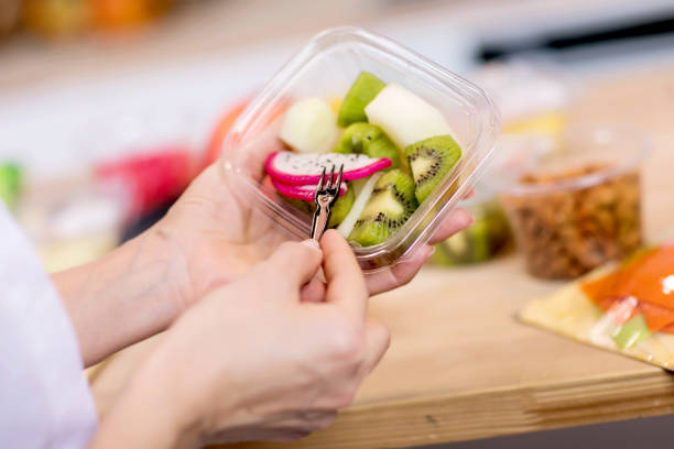 istock Hands holding Fresh fruits salad in box 1243460479
