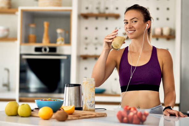 istock Happy athletic woman drinking fruit smoothie in the kitchen. 1243464425