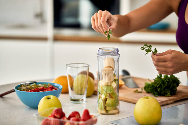 istock Close-up of woman using parsley while making smoothie in the kitchen. 1243464437