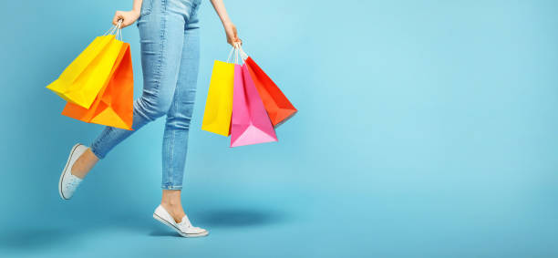 Young woman holding shopping bags Beautiful young woman and shopping bags on blue background shopping bag stock pictures, royalty-free photos & images