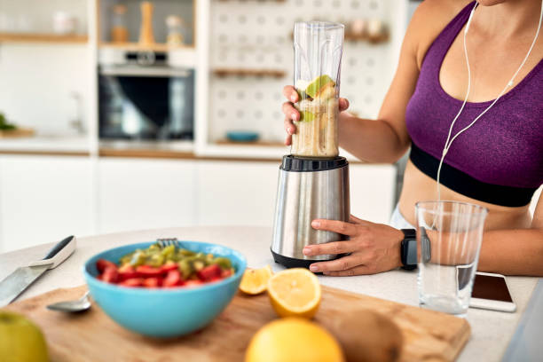 istock Unrecognizable athletic woman using blender and preparing smoothie in the kitchen. 1243466144
