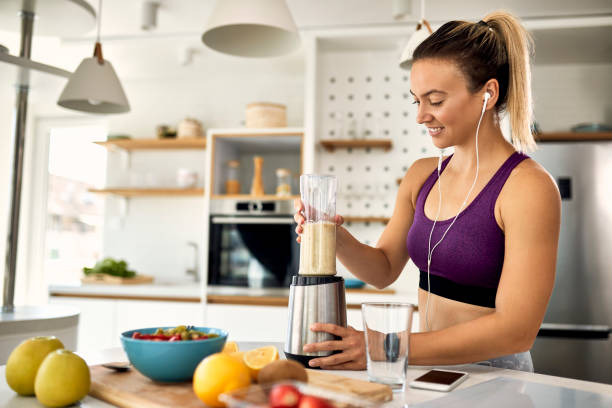 istock Happy female athlete blending fruit while preparing smoothie at home. 1243466187