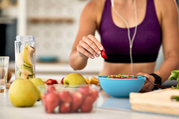 nahaufnahme der sportlerin, die obstsalat in der küche macht. - fruit salad fruit healthy eating making stock-fotos und bilder