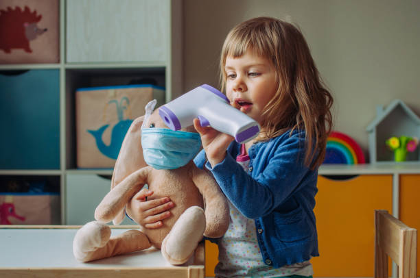 istock Toddler girl using electronic non-contact thermometer for bunny soft toy 1243477149