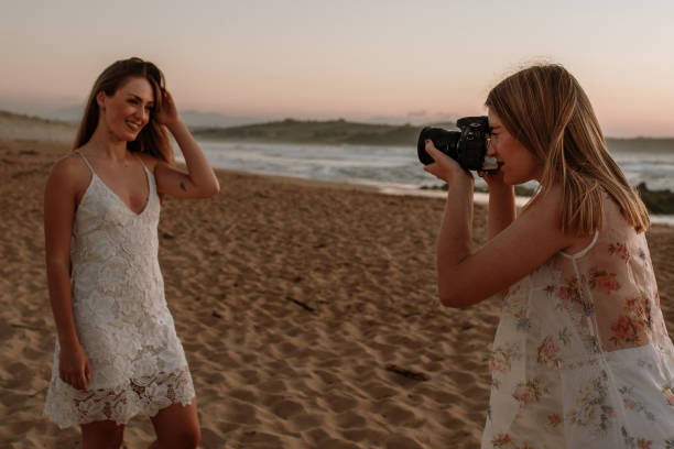 istock Two young women using a DSLR camera and posing at the beach 1243477160