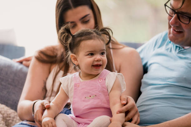 A baby sitting with her mother and her grandfather at home in Perth, Western Australia.