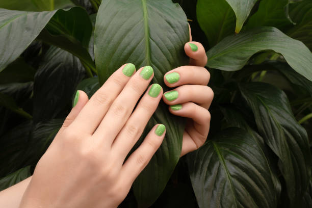istock Female hand with green glitter nail design 1243511175