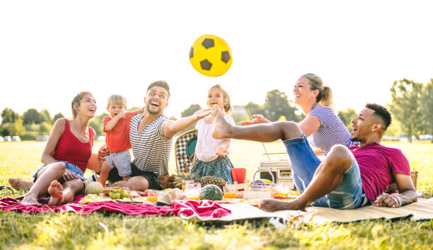 happy multiracial families having fun with cute kids at pic nic garden party - multicultural joy and love concept with mixed race people playing together with children at park - bright sunny filter - picnic family barbecue social gathering imagens e fotografias de stock