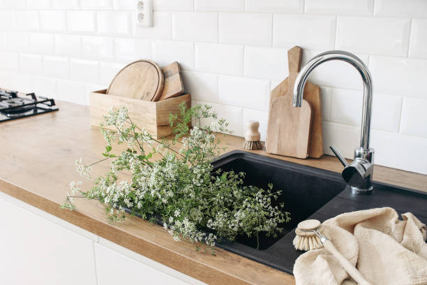 primer plano del interior de la cocina. paredes de ladrillo blanco, baldosas de metro, encimeras de madera con tablas de cortar. plantas de perejil de vaca en fregadero negro. diseño escandinavo moderno. puesta en escena del hogar, concepto de limpieza. - cerefolio agreste fotografías e imágenes de stock