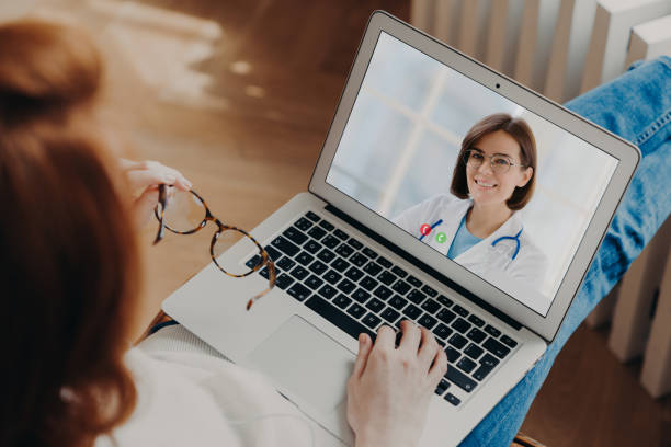 istock Unrecognizable woman has video chat with experienced doctor on laptop computer gets consultancy during quarantine discuss disease treatment. Videochatting with general practitioner. Back rear view 1243538991