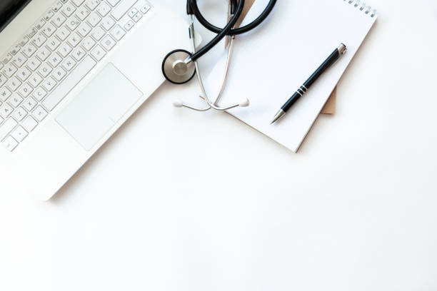 lieu de travail du médecin avec ordinateur portable et stéthoscope sur le clavier et le bloc-notes avec stylo isolé. vue supérieure. concept médical, business. - 2232 photos et images de collection