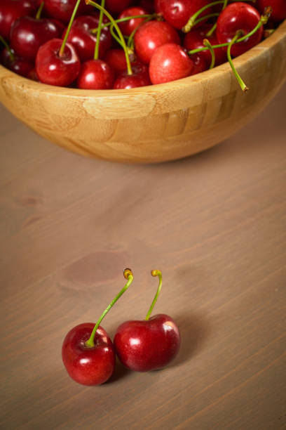 istock Green spring red cherries on wooden background selective focus cherry 1243548220
