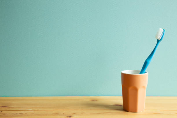 istock Blue toothbrush in cup on wooden table with mint background. copy space 1243562339